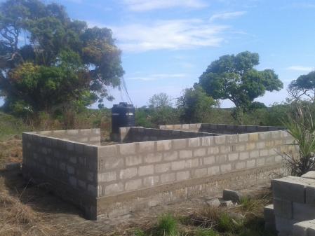 Construção das primeiras paredes. Um tanque de água de 3000 litros é visível ao fundo.